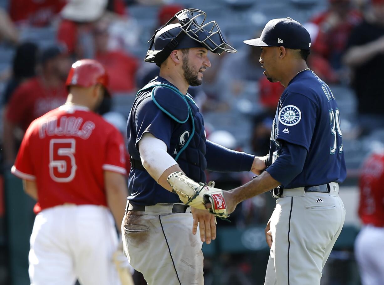 Seattle Mariners catcher Mike Zunino, center, congratulates relief pitcher Edwin Diaz, right, after Diaz struck out Los Angeles Angels designated hitter Albert Pujols, left, swinging, during the ninth inning of a baseball game in Anaheim, Calif., Sunday, July 29, 2018.