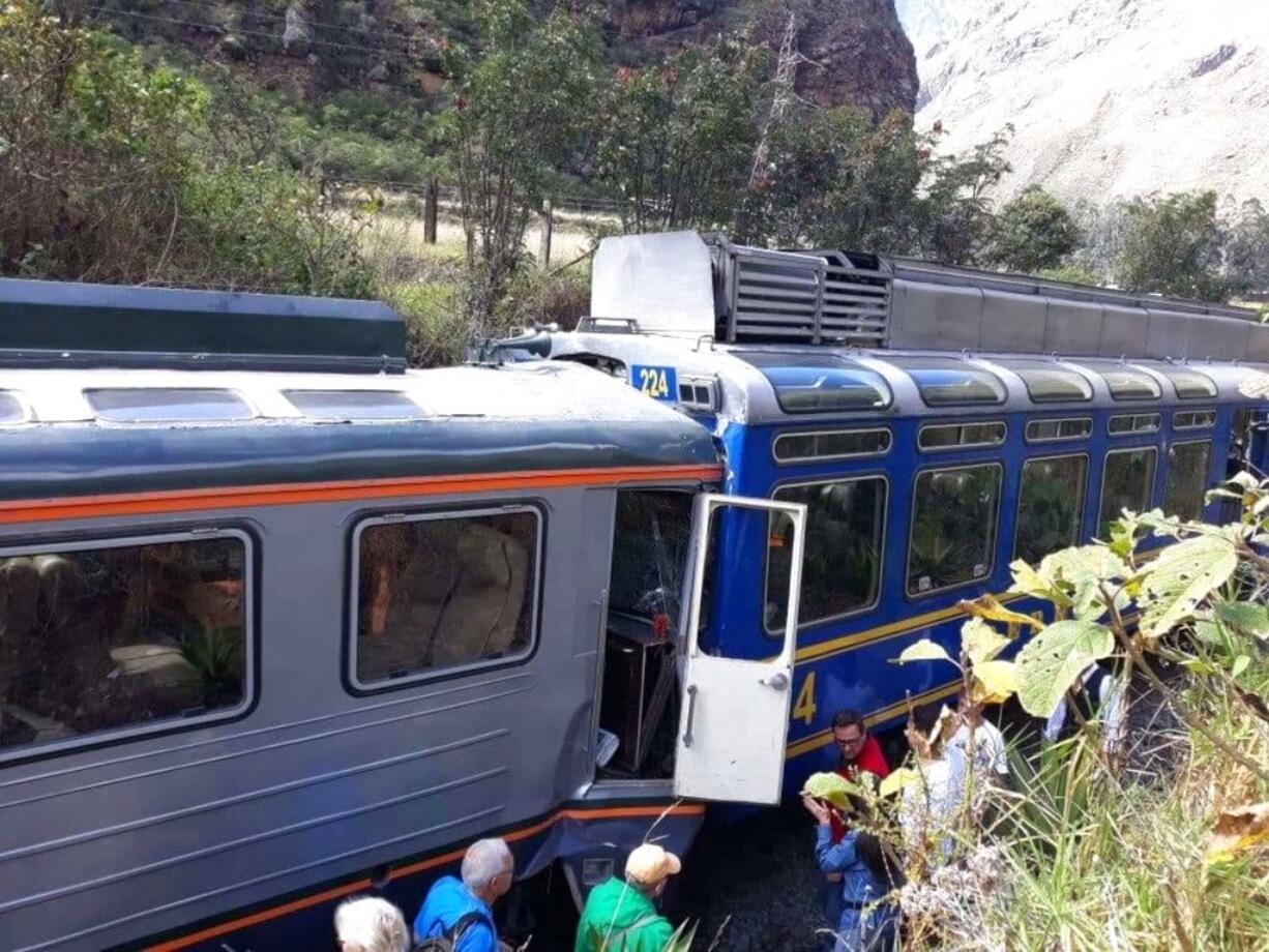 In this photo provided by the government news agency Andina, passeners observe two trains after they collided in Cuzco, Peru, Tuesday, July 31, 2018. The two trains collided near the ancient Incan citadel of Machu Picchu, a prized archaeological site in Peru visited by thousands of tourists each year.