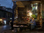 A woman sits at her shop of Andean amulets and offerings to the “Pachamama,” or Mother Earth, at the Witches’ Market in La Paz, Bolivia, on July 10. Left: Andean vessels and amulets are displayed for sale at a shop.