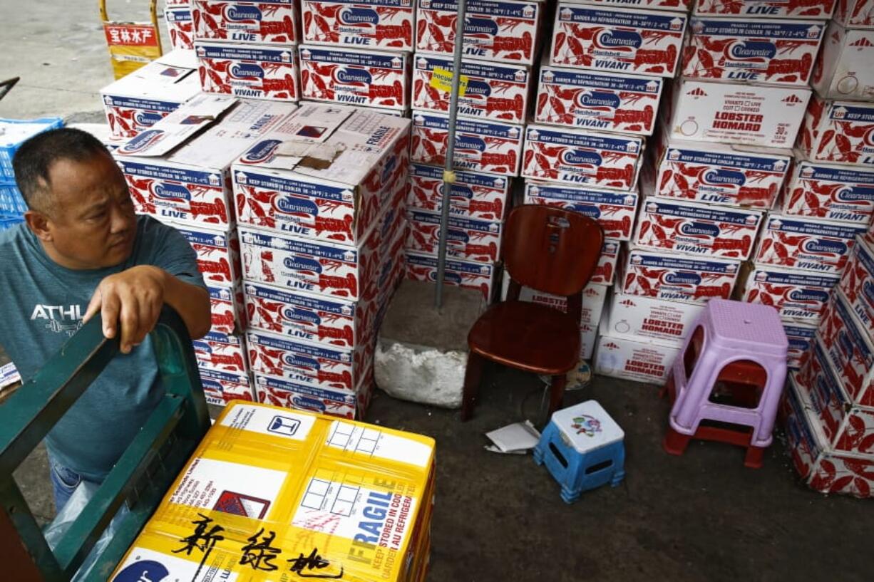 A man waits for the goods to be load on his tricycle at a dealer selling imported seafoods at the Jingshen seafood market in Beijing, Thursday, July 12, 2018. China’s government vowed on Wednesday to take “firm and forceful measures” as the U.S. threatened to expand tariffs to thousands of Chinese imports like fish sticks, apples and French doors, the latest salvo in an escalating trade dispute that threatens to chill global economic growth.