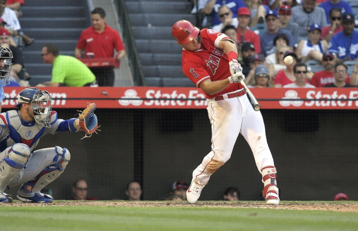 Los Angeles Angels’ Mike Trout, right, hits a solo home run as Los Angeles Dodgers catcher Yasmani Grandal watches during the sixth inning of a baseball game Saturday, July 7, 2018, in Anaheim, Calif. (AP Photo/Mark J.