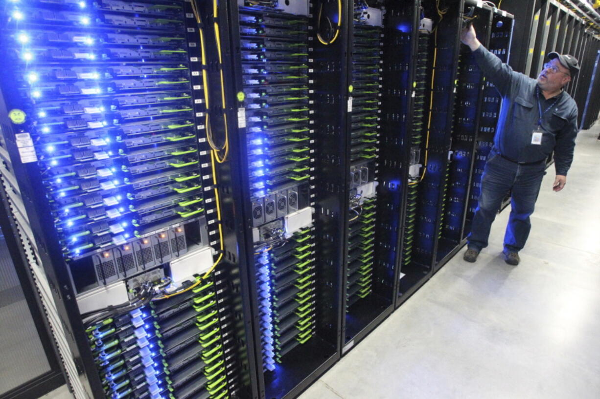 FILE - In this Oct. 15, 2013, file photo, Chuck Goolsbee, site director for Facebook’s Prineville data centers, shows the computer servers that store users’ photos and other data, at the Facebook site in Prineville, Ore. Facebook and Pacific Power are teaming up to construct solar projects that will produce enough power to offset what the social media giant consumes at its data centers in Prineville. The companies along with Oregon Gov. Kate Brown announced the deal Wednesday, July 18, 2018.