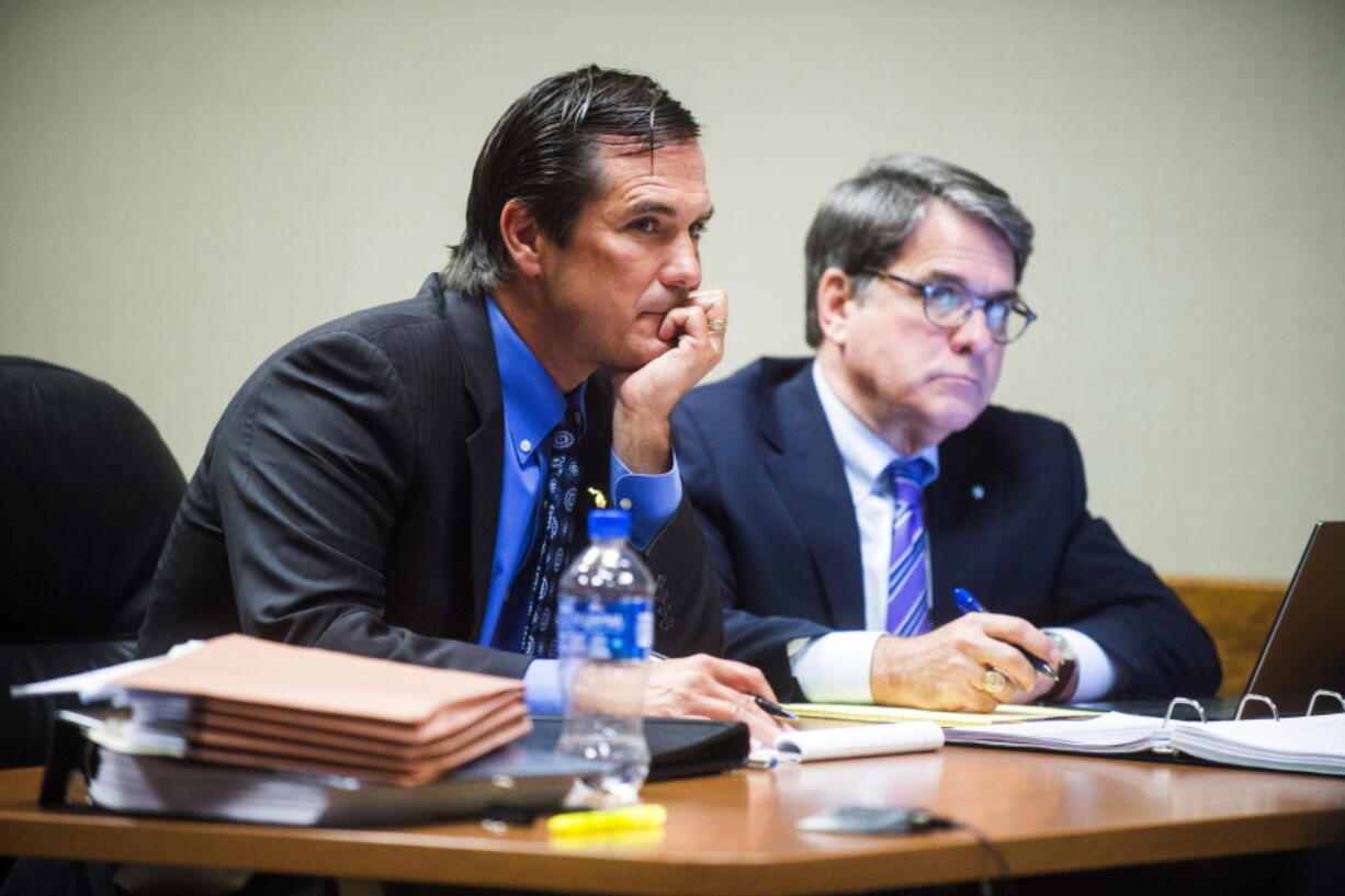 Nick Lyon, left, director of Michigan Department of Health and Human Services, listens to defense attorney John Bursch as he delivers his closing argument during Lyon's preliminary examination on Wednesday, July 11, 2018, at Genesee County District Court in Flint, Mich. The head of Michigan's health department, Lyon, is charged with involuntary manslaughter and other crimes. He's accused of not timely alerting the public about a Legionnaires' disease outbreak in the Flint area in 2014 and 2015.