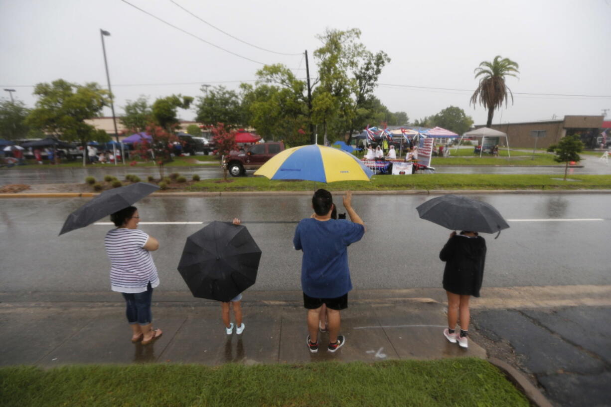 People watch the Friendswood Grand Parade during heavy rain on Wednesday in Friendswood, Texas.