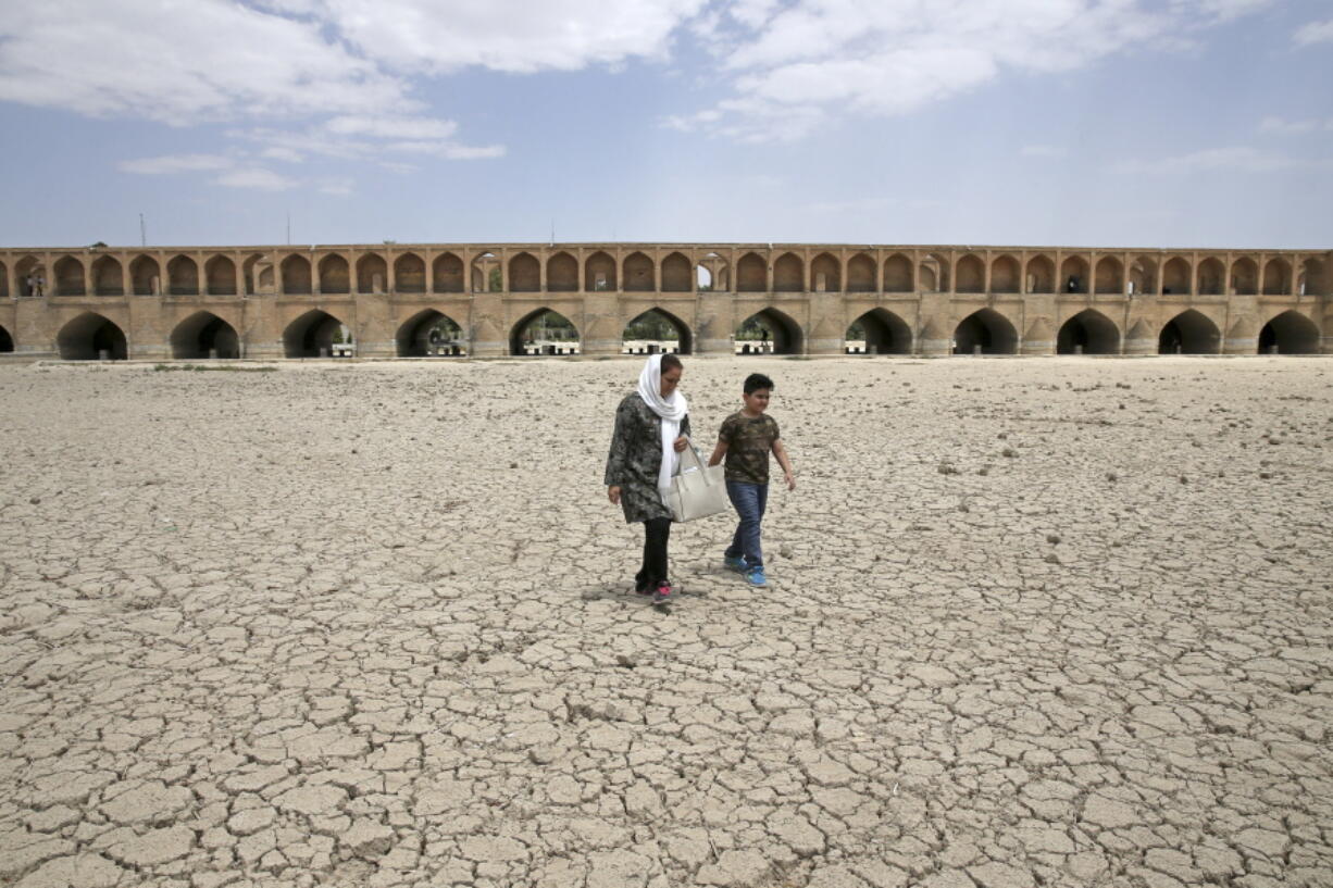 A woman and a boy walk July 10 on the dry riverbed of the Zayandeh Roud river that used to flow under the 400-year-old Si-o-seh Pol bridge in Isfahan, Iran. Farmers in central Iran are increasingly turning to protests, pleading to authorities for a solution as years of drought and government mismanagement of water destroy their livelihoods.