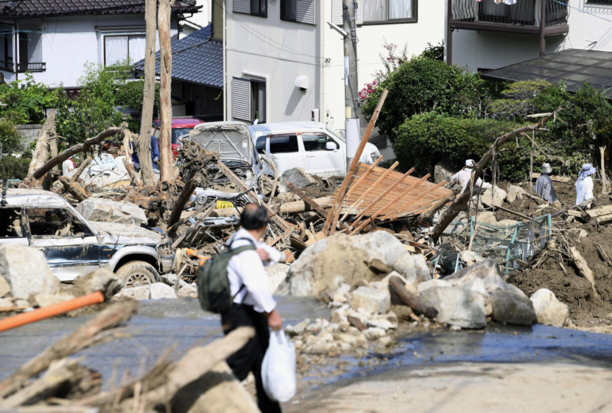 A man walks past debris from a heavy rain in Hiroshima, southwestern Japan, on Tuesday. Rescuers combed through mud-covered hillsides and near riverbanks Tuesday to look for dozens of people still missing after days of heavy rains caused flooding and mudslides in southwestern Japan.