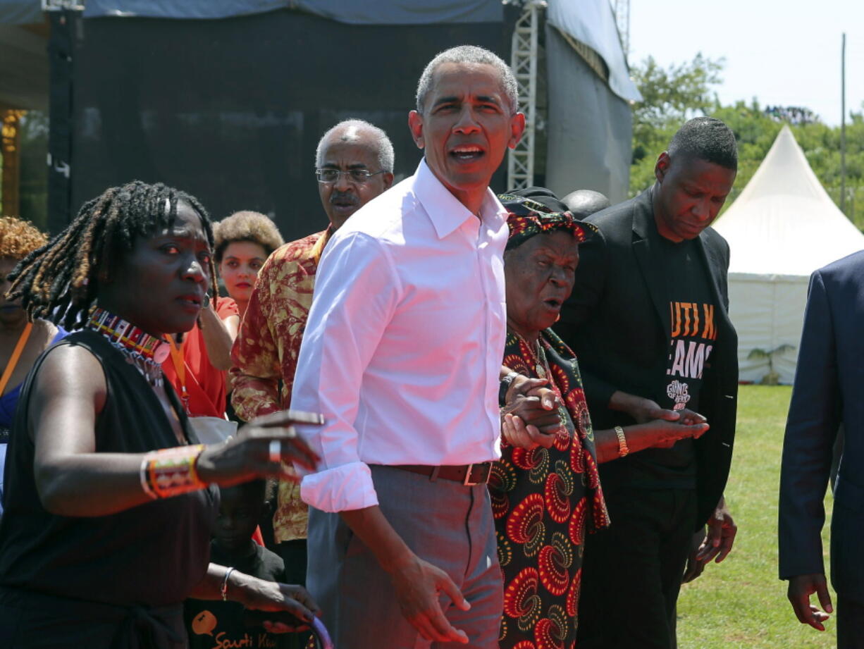 Former U.S. President Barack Obama, center, with his half sister Auma Obama, left, and her grandmother, Sarah Obama, second right, walk in Kogelo, Kenya, Monday.