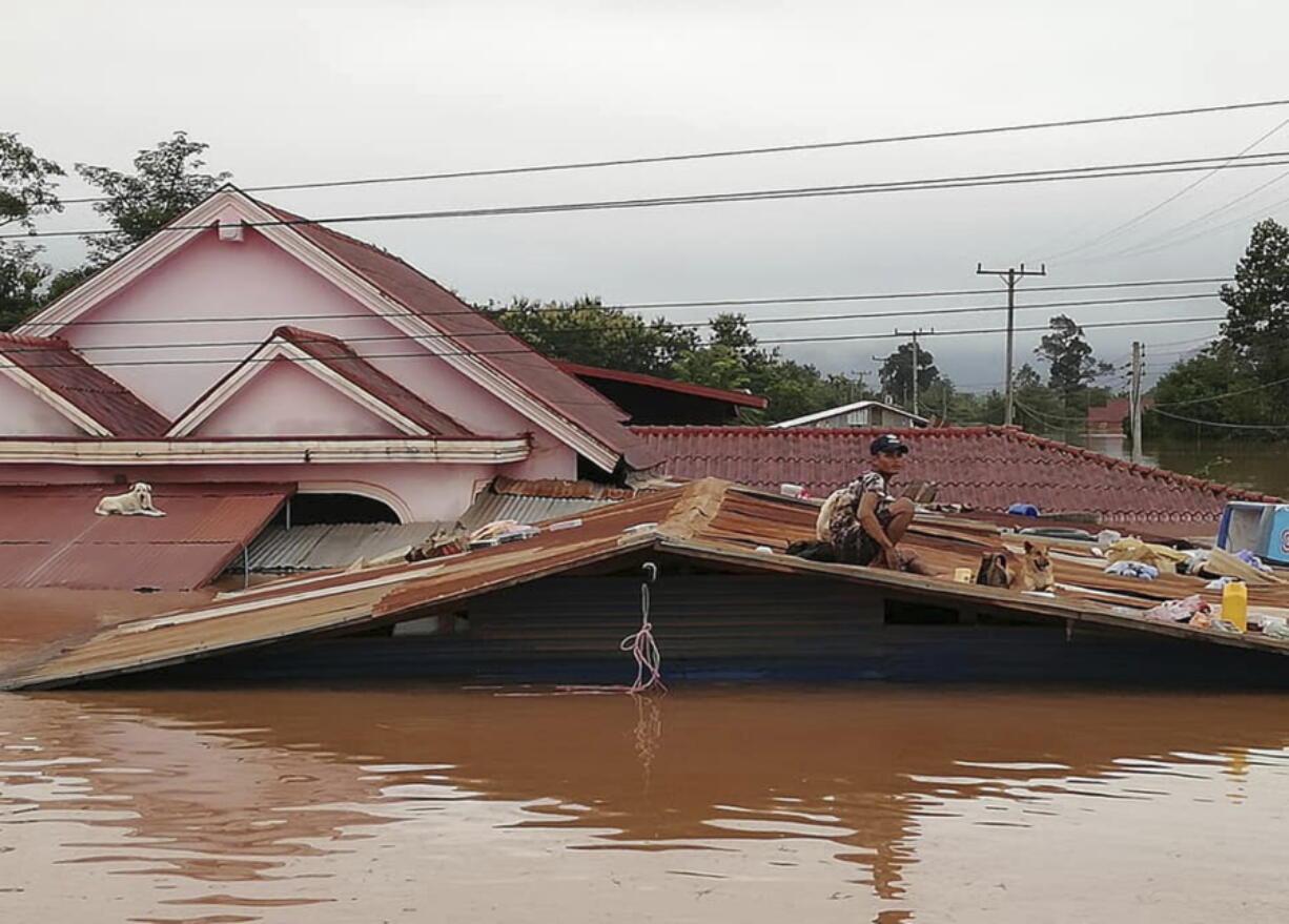 A villager takes refuge on a roof amid flood waters Tuesday in the Attapeu district of southeastern Laos.