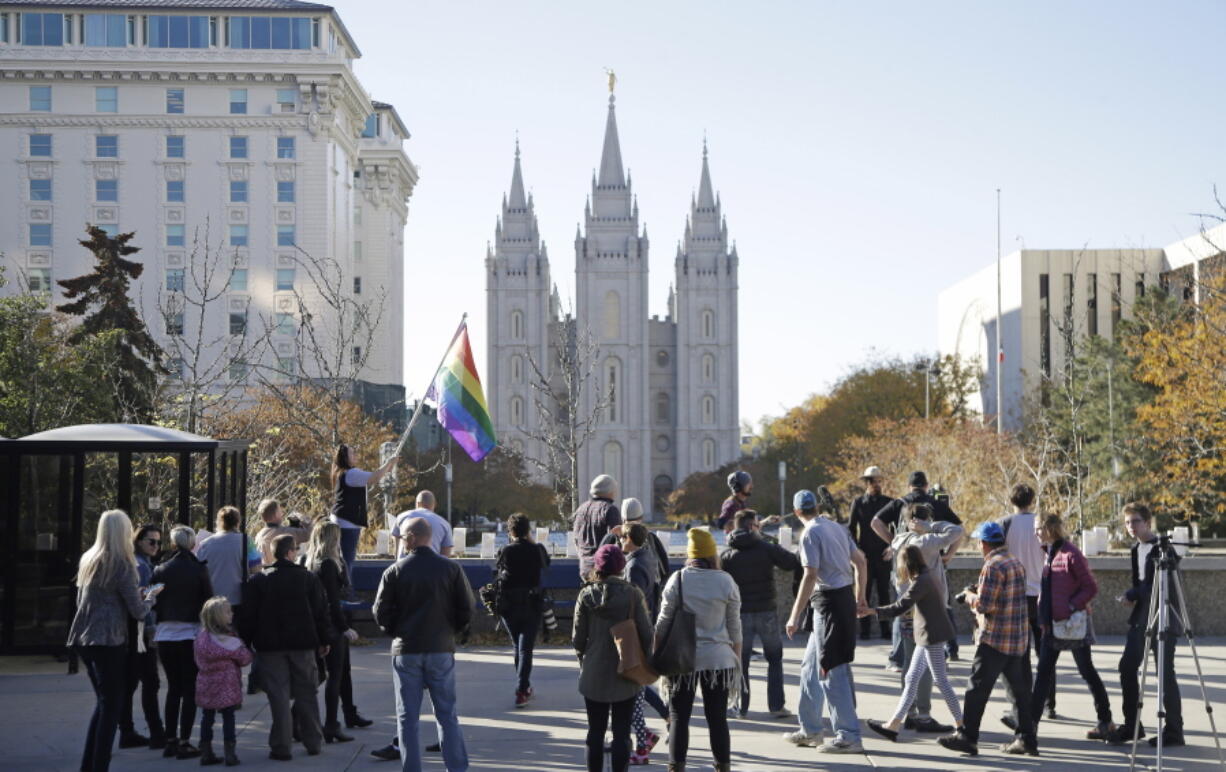 FILE - In this Nov. 14, 2015, file photo, people walk past the Salt Lake Temple after mailing resignation letters during a mass resignation from the Church of Jesus Christ of Latter-day Saints in Salt Lake City. The Mormon church’s massive genealogical database will begin accepting submissions of names of people from same-sex relationships sometime next year. The move doesn’t foreshadow any change to long-standing church opposition to gay marriage, but it is being done to ensure the databank has as much information as possible for researchers, according to a statement from The Church of Jesus Christ of Latter-day Saints.