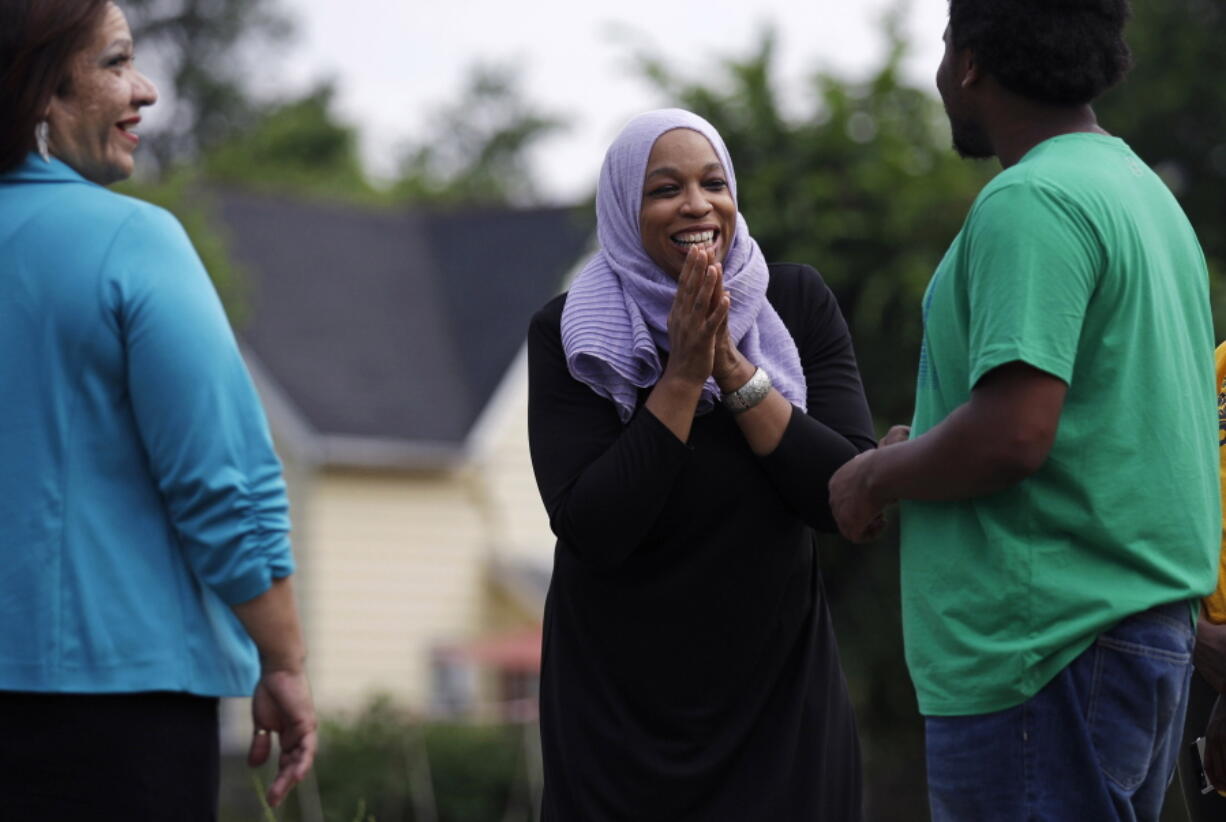 Attorney Tahirah Amatul-Wadud, who is challenging incumbent U.S. Rep. Richard Neal, D-Mass., center, talks with Dondre Scott, right, during a visit to a community garden while campaigning in the Mason Square neighborhood of Springfield, Mass., on Monday. At left is Ivette Hernandez, who is running for Mass. House of Representatives.