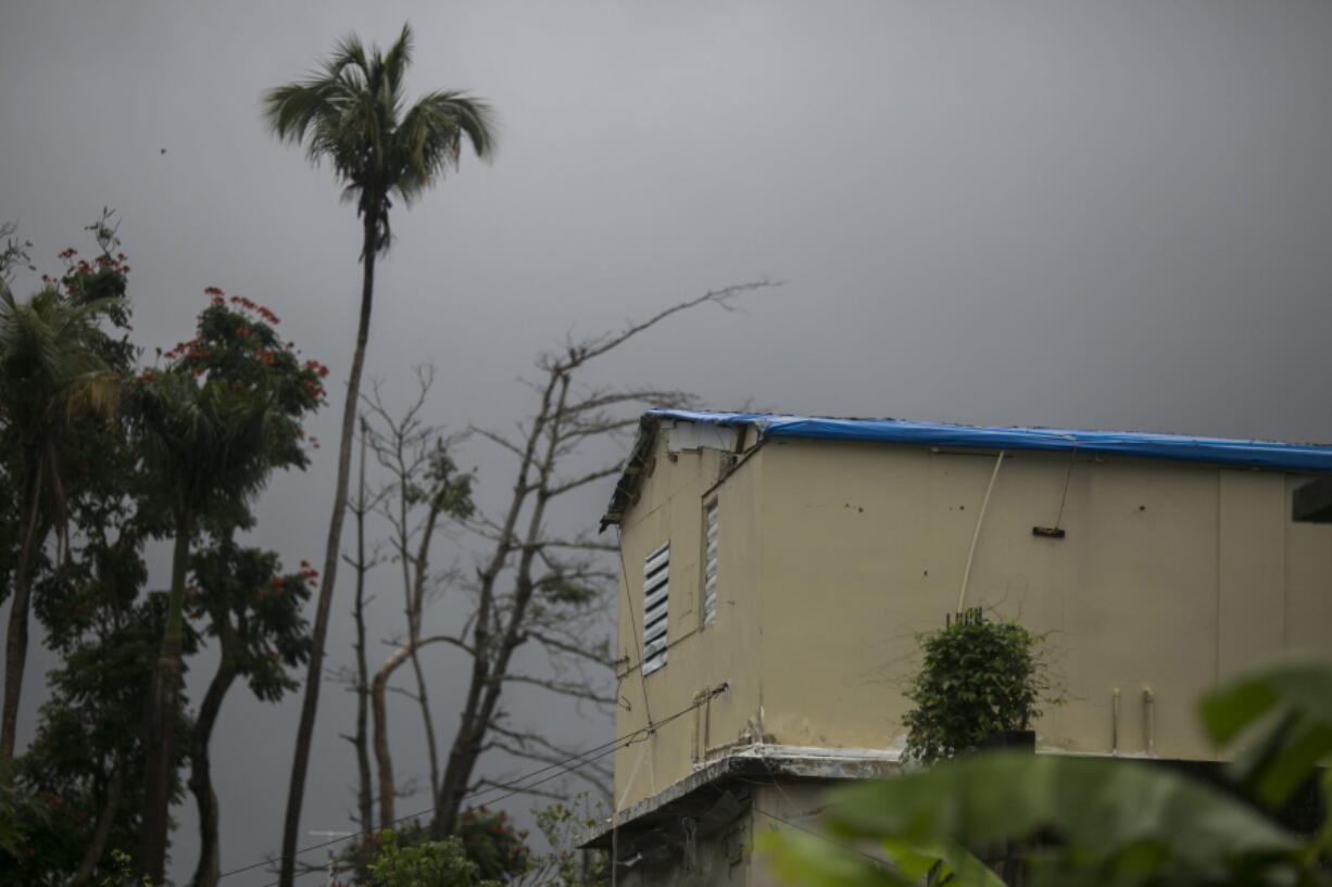 The remnant of Tropical Storm Beryl continues its way over a home still using a blue tarp for a roof that was previously damaged by Hurricane Maria, in Yabucoa, Puerto Rico, Monday, July 9, 2018. Almost four inches of rain were reported without any significant events reported. (AP Photo/Dennis M.