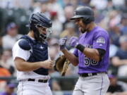 Colorado Rockies’ Noel Cuevas, right, celebrates as he reaches home after hitting a three-run home run on a pitch from Seattle Mariners starter James Paxton during the seventh inning of a baseball game, Saturday, July 7, 2018, in Seattle.