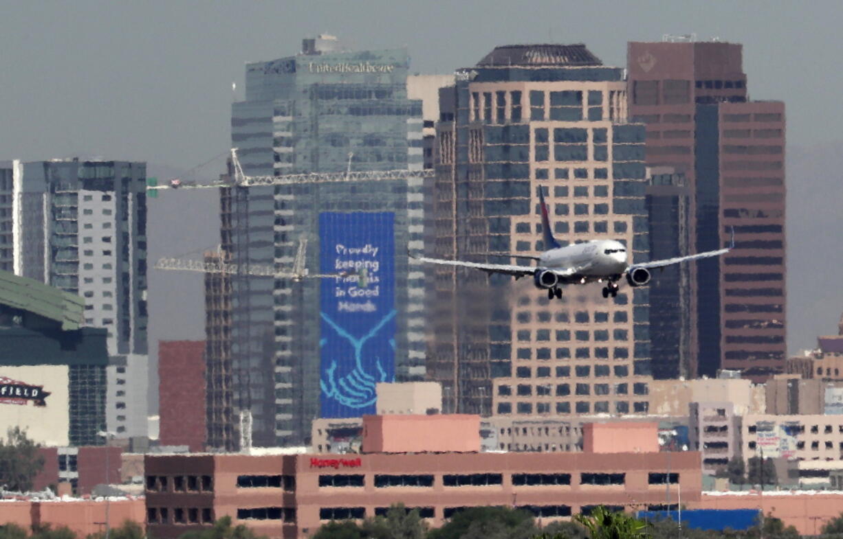 Heat ripples blur the downtown skyline Monday as a jet lands in Phoenix, Ariz., amid temperatures exceeding 100 degrees in the morning hours. Already devilishly hot for being in the Sonoran desert, Arizona’s largest city is also an “urban heat island,” a phenomenon that pushes up temperatures in areas covered in heat-retaining asphalt and concrete. Phoenix officials say they are tackling urban warming, monitoring downtown temperatures, planting thousands of trees and capturing rainwater to cool off public spaces.