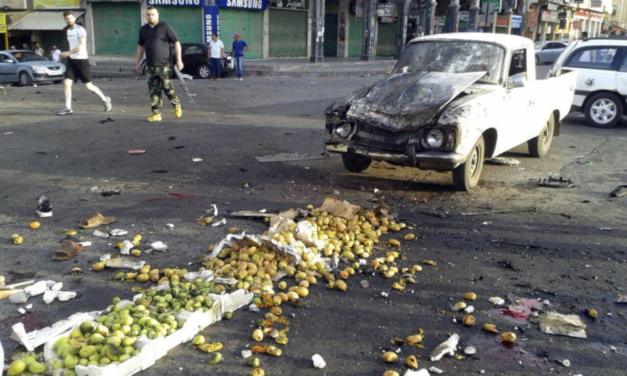 In this photo released by the Syrian official news agency SANA, Syrians inspect the site of a suicide attack in Sweida, Syria, Wednesday, July 25, 2018. Syrian state media say dozens of people have been killed in a suicide attack in the country’s south, blaming the bombing on Islamic State militants.