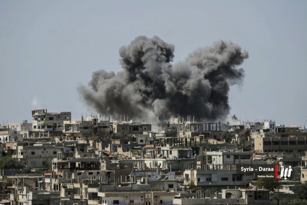 FILE - This Thursday, July 5, 2018 file photo provided by Nabaa Media, a Syrian opposition media outlet, shows smoke rising over buildings that were hit by Syrian government forces bombardment, in Daraa province, southern Syria. Syrian activists and state media said Thursday, July 12, 2018 that the rebels have agreed to surrender Daraa, the first city to revolt against President Bashar Assad with Arab Spring-inspired protests seven years ago, to government forces.