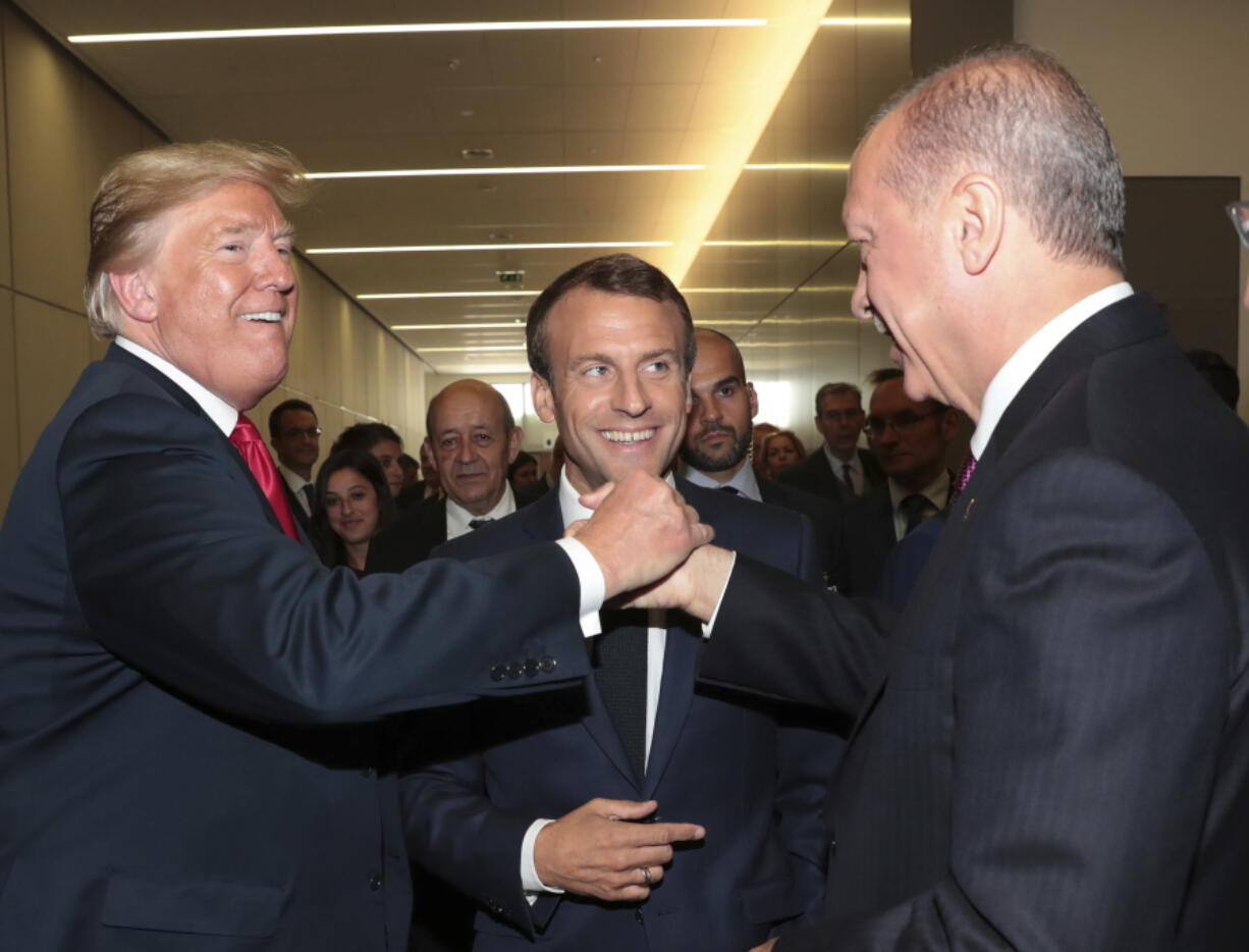 U.S. President Donald Trump, left, shakes hands with Turkey’s President Recep Tayyip Erdogan, right, as French President Emmanuel Macron, center, watches on the sidelines of a summit of heads of state and government at NATO headquarters in Brussels Belgium. Plenty of U.S. presidents have created commotion in their travels abroad, none so much as President Donald Trump. Historians say Trump’s tumultuous trip across Europe smashed the conventions of American leaders on the world stage. The president’s “America first” approach to foreign policy left him seeming to accept the word of a hostile power over his own intelligence agencies, insulting allies and sowing doubts about his commitment to the NATO alliance.