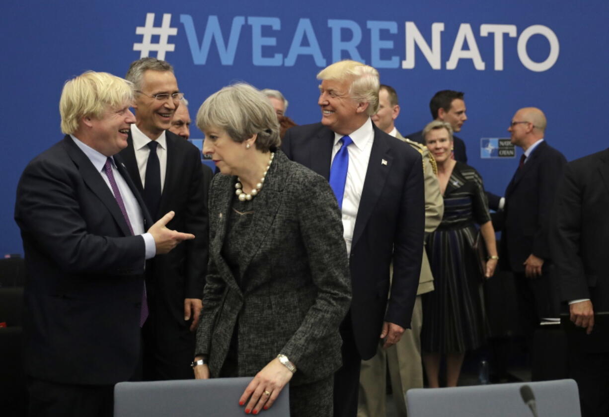 FILE - In this May 25, 2017, file photo, U.S. President Donald Trump jokes with British Foreign Minister Boris Johnson as British Prime Minister Theresa May walks past during a working dinner meeting at the NATO headquarters during a NATO summit of heads of state and government in Brussels. Threatening to upend generations of global order, Trump’s week-long European trip will test the strained bonds with some of the United States’ closest allies before putting him face-to-face with the leader of the country whose electoral interference helped put him in office.