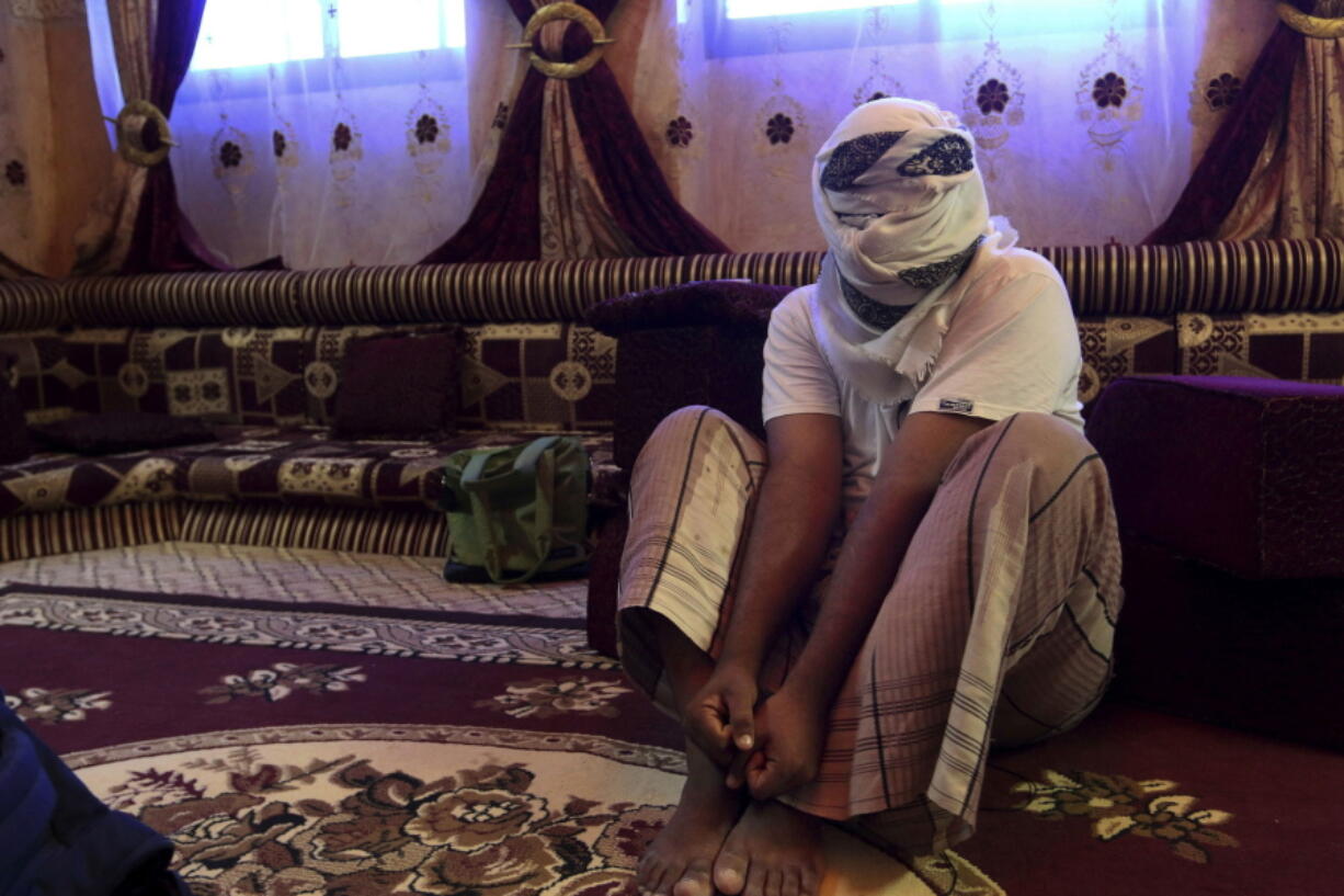 A former detainee covers his face for fear of being detained again as he shows in May 2017 how he was kept in handcuffs and leg shackles while being held in a secret prison in the Yemeni city of Mukalla.