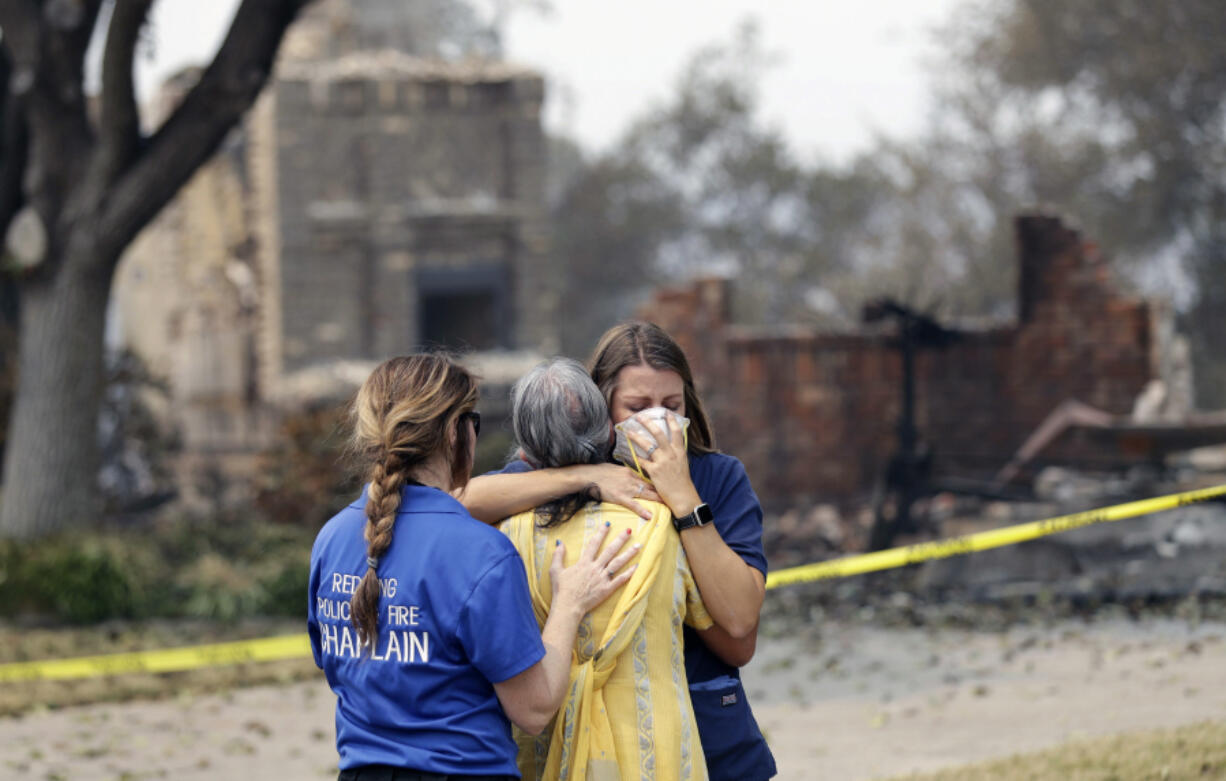 A resident, in yellow, wishing not to be identified, is comforted after seeing her fire-ravaged home for the first time Thursday, Aug. 2, 2018, in Redding, Calif.