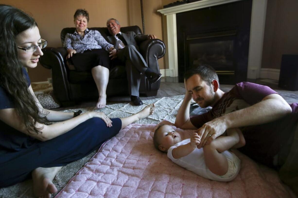 Brian Stoll plays his his 5-month-old daughter, Everly, as his wife, Rachael, looks on while her mother, Michelle Bacca-Llamas, and stepfather, Hector Llamas, laugh from the couch at their home on July 15 in West Jordan, Utah.