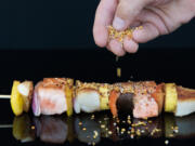 Chef Todd Gray sprinkles his version of manna on a seafood kebab at Manna, Gray’s restaurant in the Museum of the Bible in Washington, D.C. Dixie D.