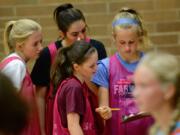 Prairie junior Maya Davis shows her teammates Alyssa Talkington and Haley Reed a clipboard containing results of assessments.