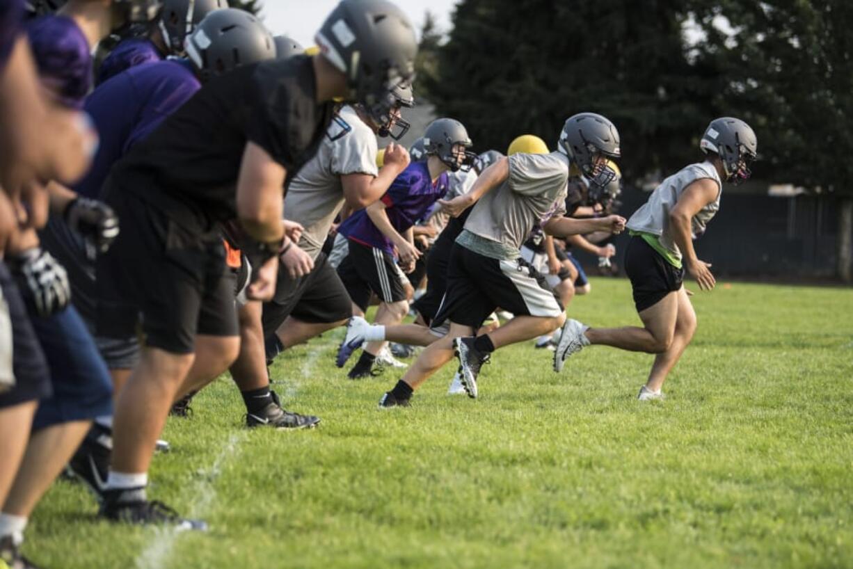 Heritage players run conditioning drills during a practice at Heritage High School on Thursday night, Aug. 16, 2018.