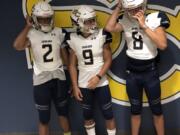 Seton Catholic players (left to right) Tyvauntae Deloney. Taj Muhammad and Mikey Silveira Jr. try on the game uniforms for the first time of the 2018 football season on Thursday at Seton Catholic College Prep.