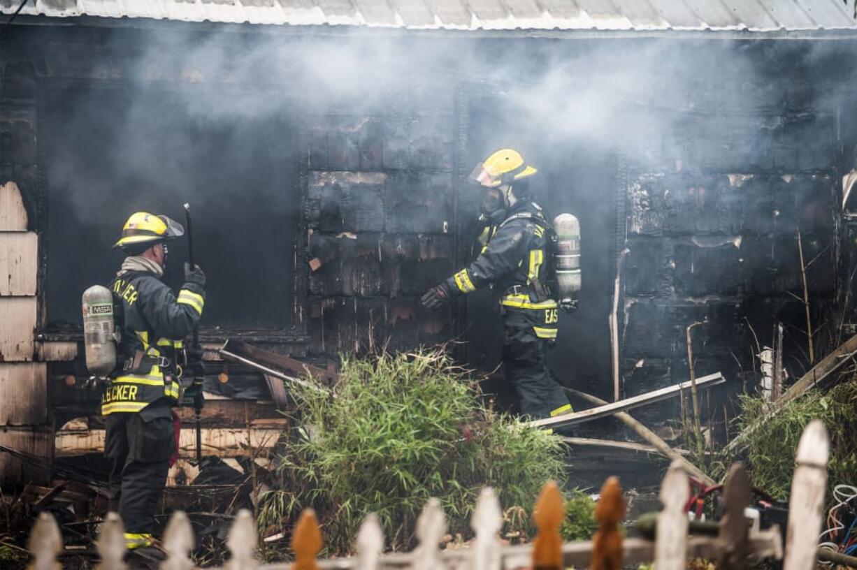 Firefighters with the Vancouver Fire Department combat a house fire at 3605 N.E. 44th St., Monday.