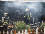 Firefighters with the Vancouver Fire Department combat a house fire at 3605 N.E. 44th St., Monday.