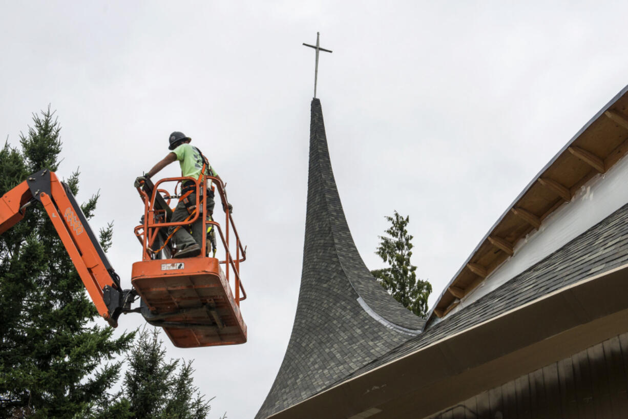 A contractor working at Vancouver United Church of Christ prepares to install new windows on July 19. The church’s west steeple was damaged by fire in May 2016.