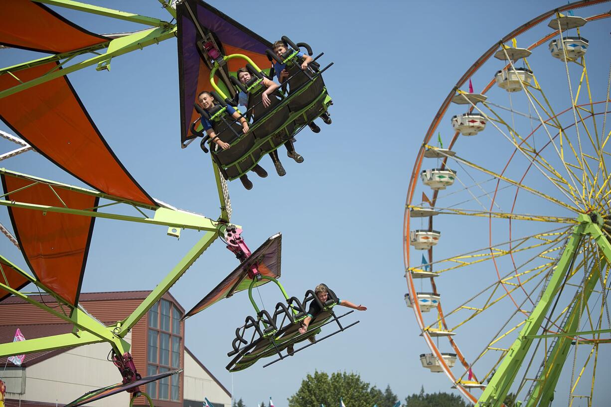 Hailey Hartzell, top from left, Maya Hartzell, and Connor McKay, all of Monroe, Wash., take the Cliff Hanger for a spin while enjoying the rides at the Clark County Fair on Monday afternoon, Aug. 6, 2018. The trio said they were having fun showing their cows at the annual event, which lasts through Aug. 12.