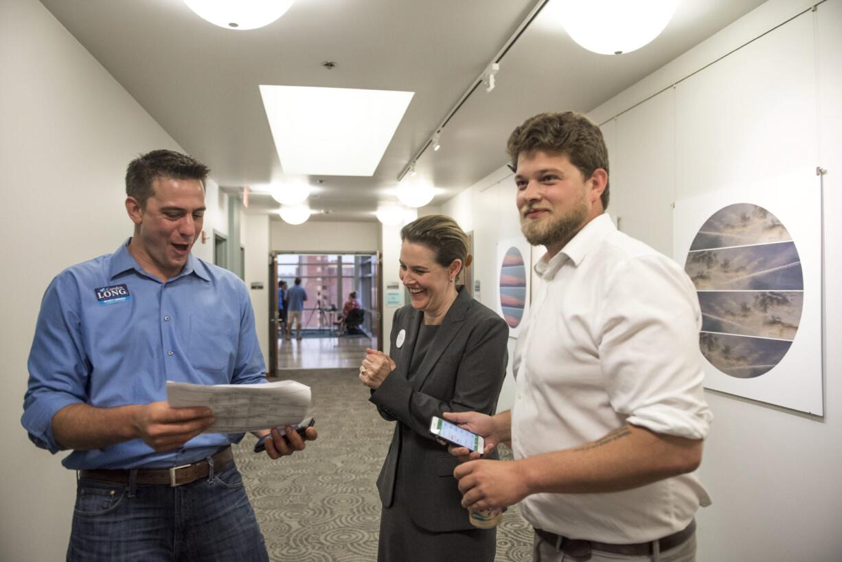 Campaign manager Wyatt Arnall, from left, Democratic candidate for the 3rd Congressional District Carolyn Long and campaign consultant Parker Butterworth react to the election results at the Clark County Public Service Center on Tuesday night (Nathan Howard/The Columbian)