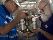 Chuck Bristol of Vancouver, left, brought this century-old family heirloom to the Repair Cafe, where he helped skilled volunteer Dick Hamlet of Camas — a retired software engineer and college professor at Portland State University — rewire the whole thing.