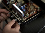 Volunteer Mike Farabee of Vancouver, a retired design engineer, tries to repair Kathy Roussos’s decades-old radio, which once belonged to her mother. Farabee had to send Roussos away with the name of a part to buy, and she promised she would; she said she’s she’s determined to fix the radio, rather than replace it.