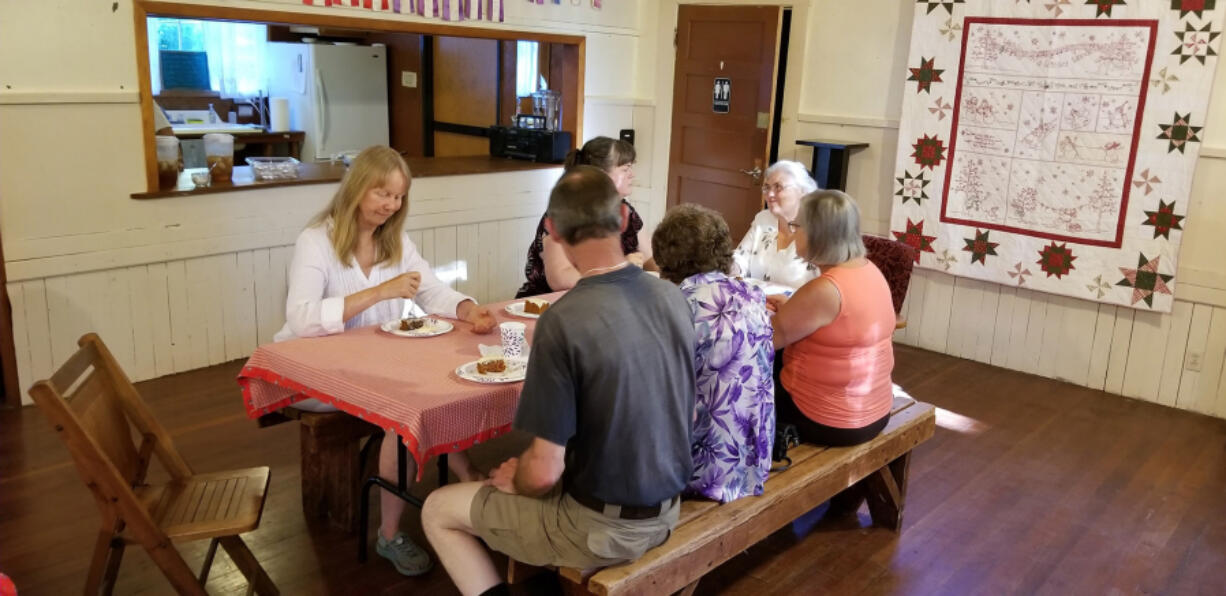 Battle Ground: Members of the Venersborg Historic Preservation Society and the Frank L. and Arlene G. Price Foundation enjoy some cake while celebrating an $11,000 grant from the foundation to fix up the Venersborg Schoolhouse roof. Hanging on the wall next to their table is a quilt the society will raffle to support upkeep of the site.