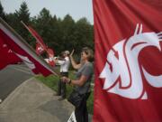 Lisa Abrahamsson, assistant director of development and alumni relations, joins Erich Orth of the class of 1999 to wave the Washington State University banner on Monday morning at Washington State University Vancouver. Dozens of WSU staff, alumni and friends turned out for the daylong ritual. Held on the first day of classes, the volunteers took hourlong turns standing on three street corners leading to the Salmon Creek campus, welcoming new and returning students.