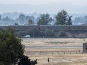 A pedestrian walks near the Fort Vancouver Stockades under lingering smoke on Tuesday.