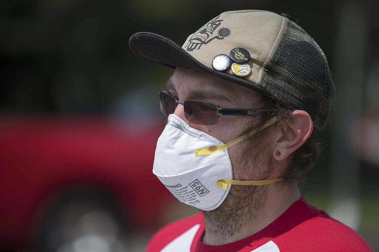 Vancouver resident Zach Hipple protects himself from hazy conditions created by wildfire smoke while on his way to join the demonstration outside the Kaiser Permanente Cascade Park office Tuesday afternoon. Hipple said he has asthma and the mask helped combat the effects of the smoke.