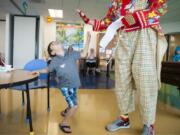 Joaquin Simpson, 6, of Pendleton, Ore., looks up at Stretch the clown, played by Ray Zimmerman of Battle Ground, during a magic show at the Shriners Hospital for Children in Portland.