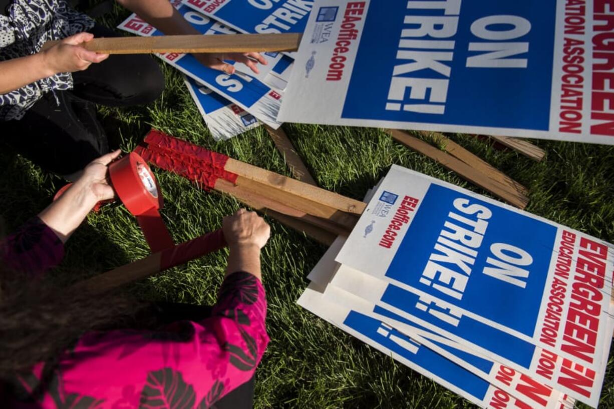 Cristy Horton, left, and Crystina Kelsey, teachers at Riverview Elementary School, make signs after the Evergreen Education Association general membership meeting at Evergreen High School in Vancouver on Thursday. Teachers in the district will be on strike effective Tuesday, the first day of school.