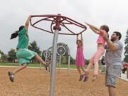 Children play at the grand opening of Otto Brown Neighborhood Park. Bryan Kast, right, whose family helped name the park, plays with his daughters — from left, Zeana, 8, Kiyla, 6, and Inga, 7. The park is 7.9 acres and named after Otto Alexander Brown, a Hockinson native who made a wooden bicycle.