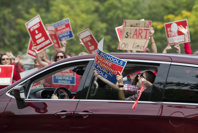 A supporter of teachers shows solidarity while passing by the rally outside the Jim Parsley Center on Monday afternoon, Aug. 27, 2018.