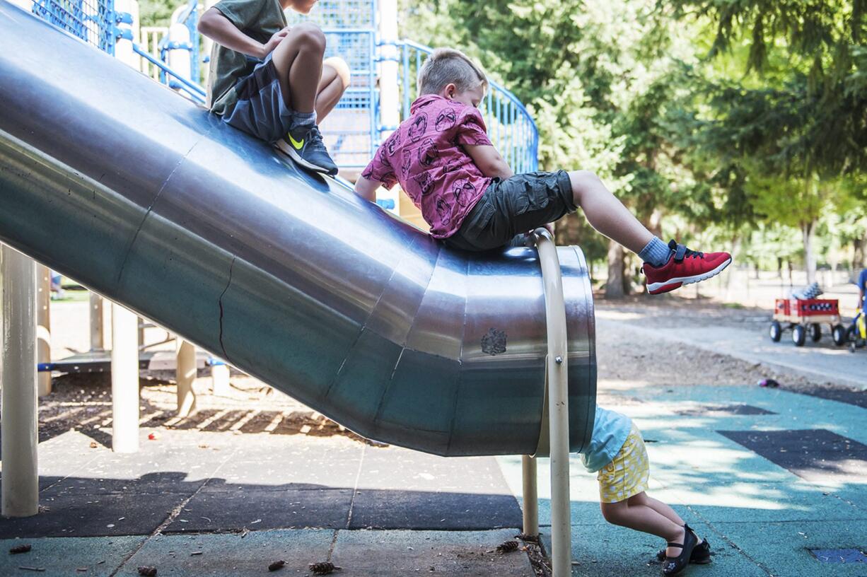 Grayson Budnick, 5, center, crawls down the top of a slide with other kids at LeRoy Haagen Memorial Park while Project Transformation served lunch and provided games on Wednesday afternoon, Aug. 29, 2018.