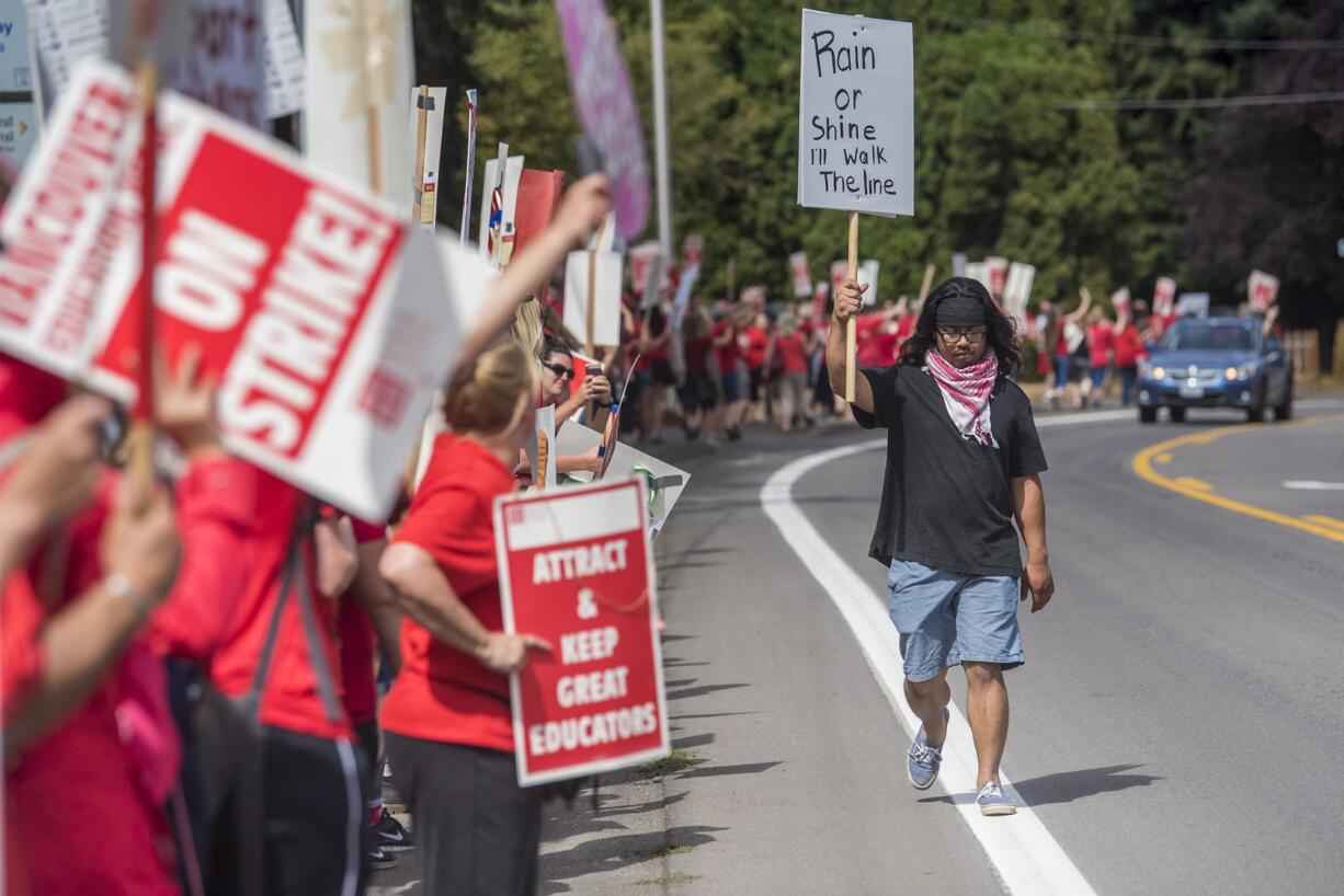 Community activist Anthony Licerio walks the picket line in support of rallying teachers in front of the Vancouver Public Schools' Administration Building on Friday afternoon.