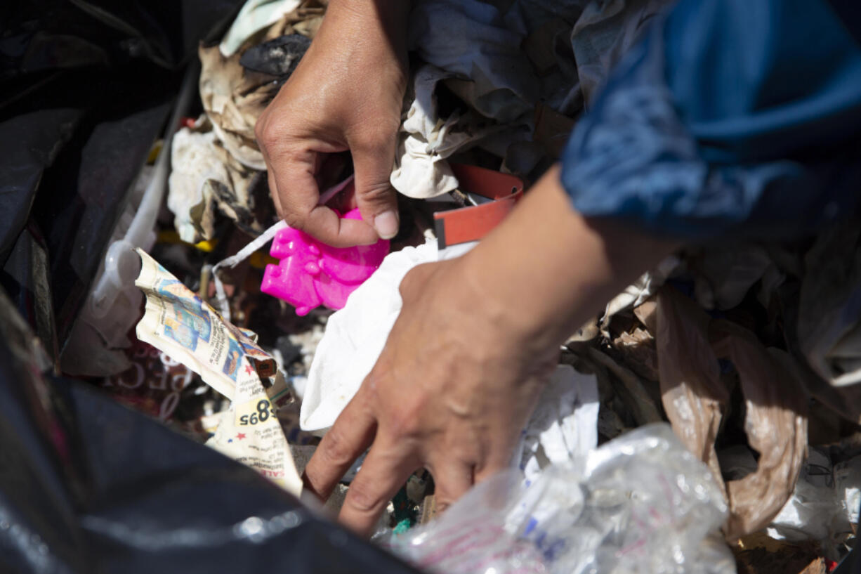 Pooka Rice digs through the bag of trashed picked up during a monthly marine debris survey and holds an elephant-shaped beach toy. Rice said beach toys are among the most common items she finds left on the beach.