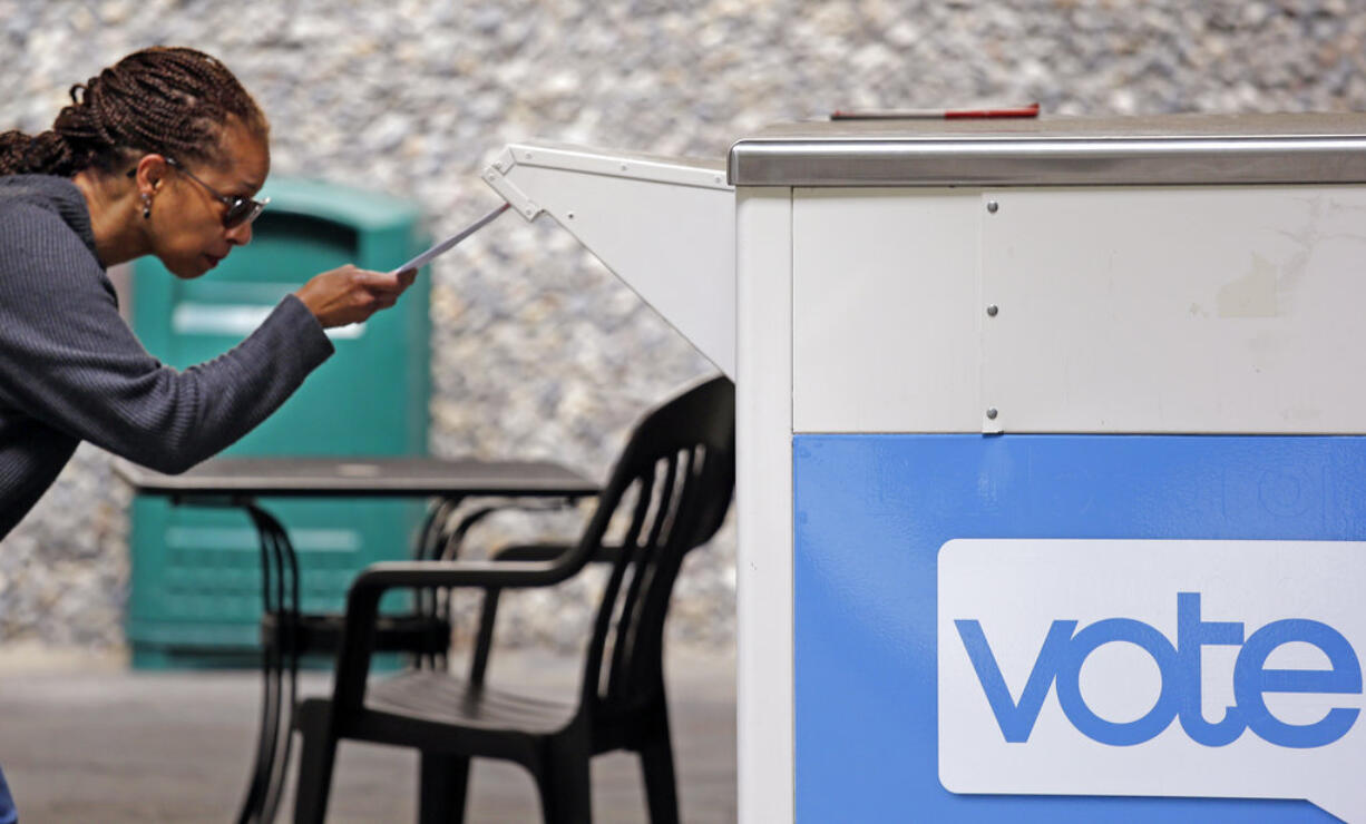 FILE - In this Tuesday, Aug. 2, 2018, file photo Eudora Carter inserts her ballot into a drop-off voting box in Seattle. Washington voters will decide which candidates advance to the November ballot in 10 congressional races, a U.S. Senate seat and dozens of legislative contests in the state's primary election.