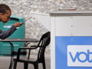 FILE - In this Tuesday, Aug. 2, 2018, file photo Eudora Carter inserts her ballot into a drop-off voting box in Seattle. Washington voters will decide which candidates advance to the November ballot in 10 congressional races, a U.S. Senate seat and dozens of legislative contests in the state's primary election.