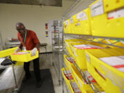 Marvin McKinly stacks ballots from Washington state's primary election on racks after they were run through a sorting machine, Tuesday, Aug. 7, 2018, at King County Election headquarters in Renton, Wash. Voters will decide which candidates advance to the November ballot in 10 congressional races, a U.S. Senate seat and dozens of legislative contests. (AP Photo/Ted S.