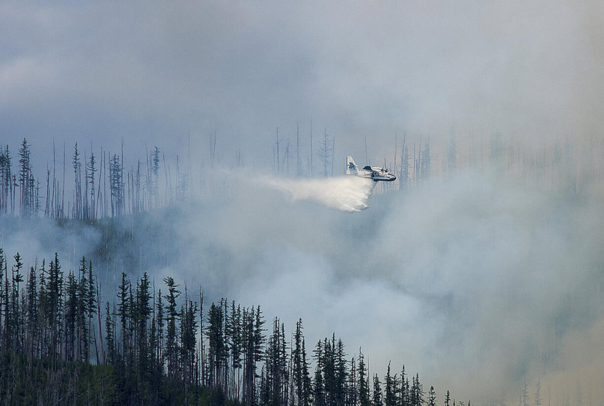 In this photo taken Sunday, Aug. 12, 2018, an air tanker drops water over a wildfire burning in Glacier National Park, Mont. The fire was started by lightning on Saturday night and forced the evacuation of the Lake McDonald Lodge and closed part of the scenic Going-to-the-Sun Road in the park.